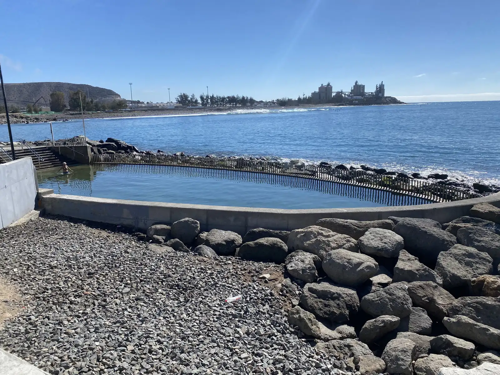 Seawater swimming pool on the Arguineguín shore with the cement works at Santa Águeda across the bay