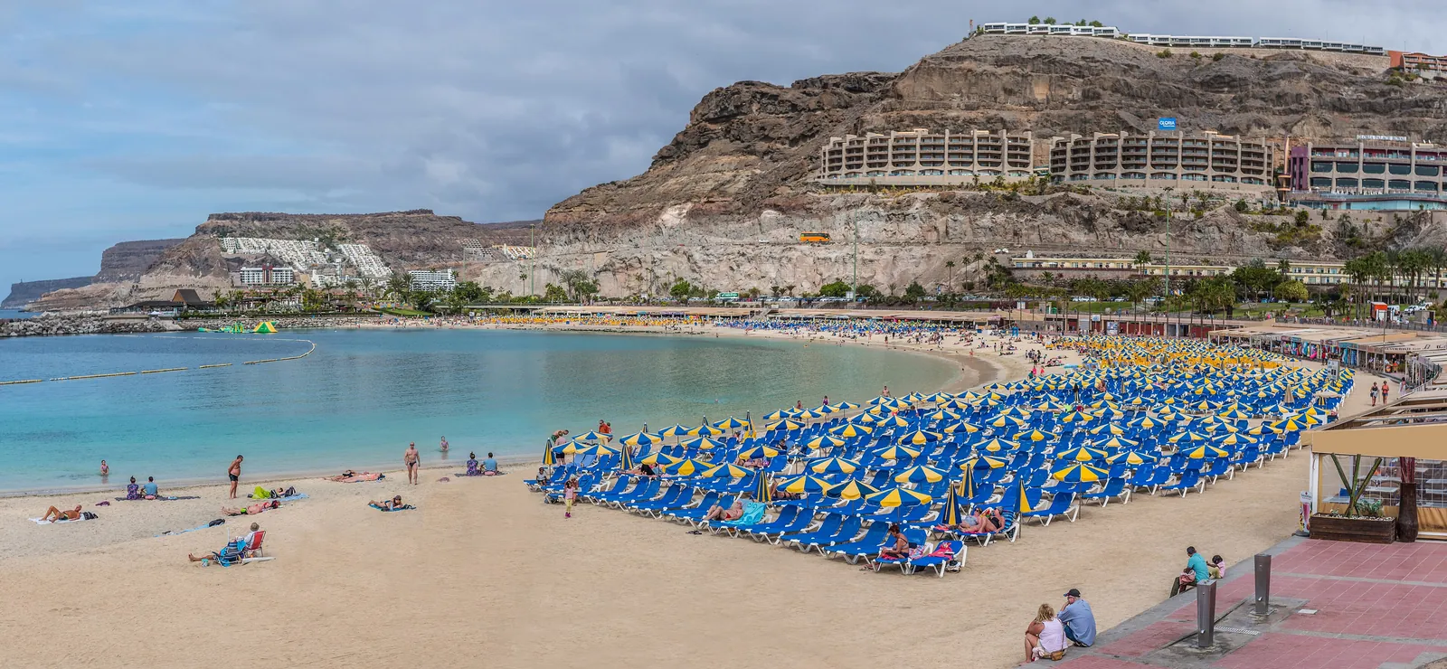 Rows of blue sunbeds on Amadores beach, a sheltered crescent of white sand and calm water