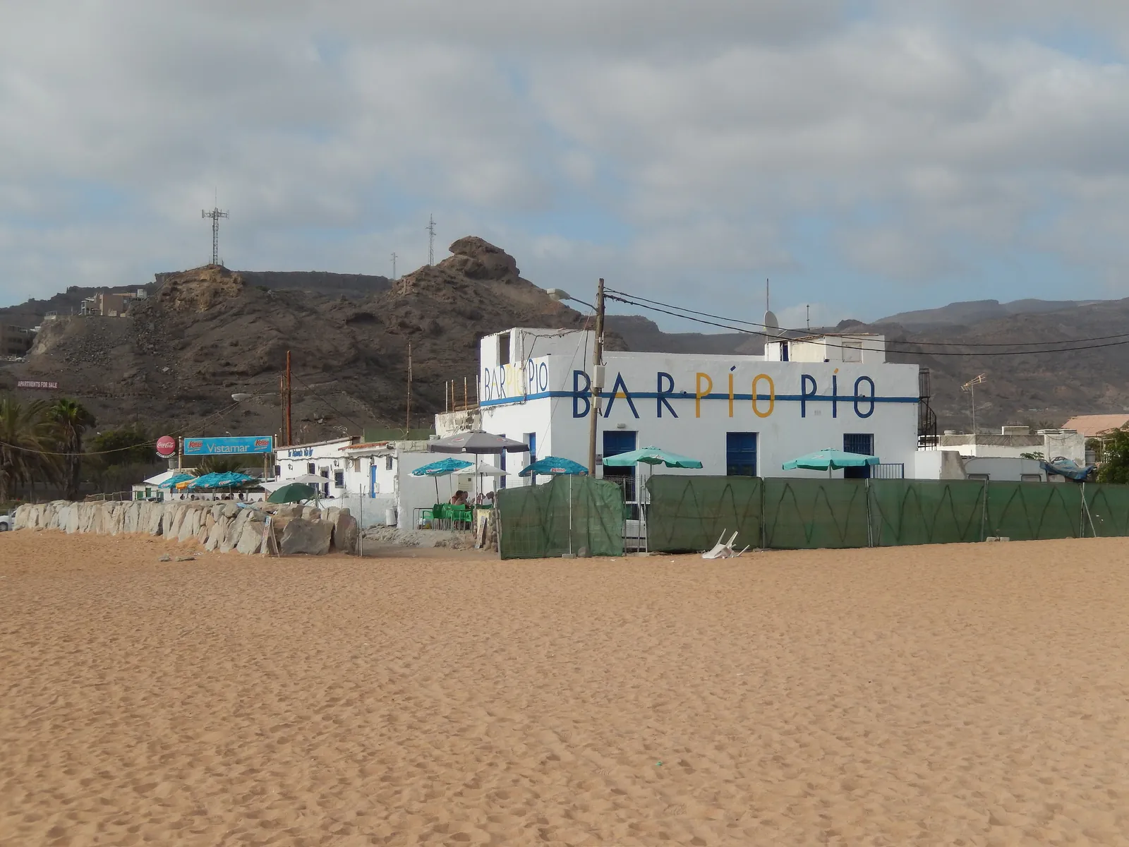 Golden sand on Playa de Tauro with a beach bar and dry hills behind