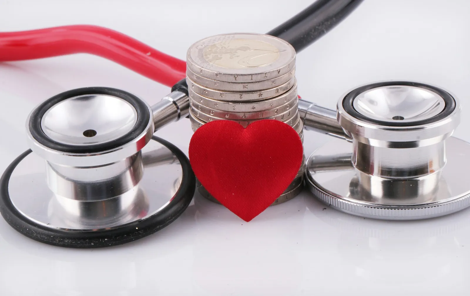 Stethoscope and a red heart on a stack of euro coins