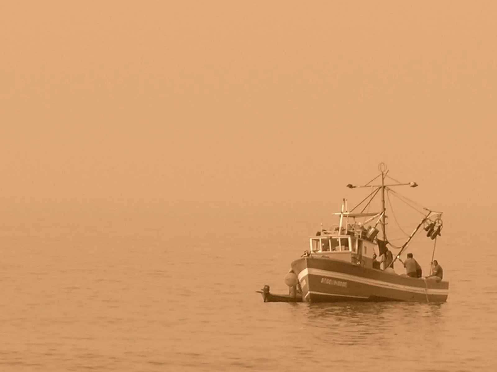 Fishing boat on a calm sea in an orange haze of Saharan dust