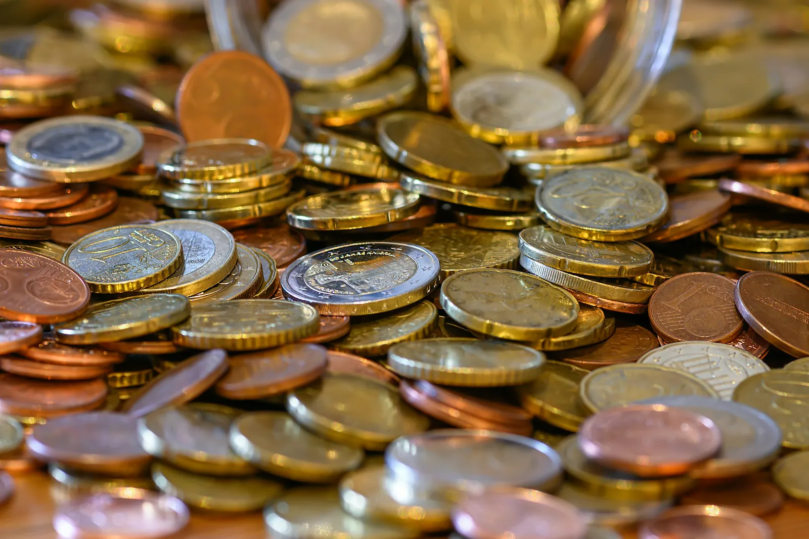 Heap of euro coins in copper and gold tones on a wooden table