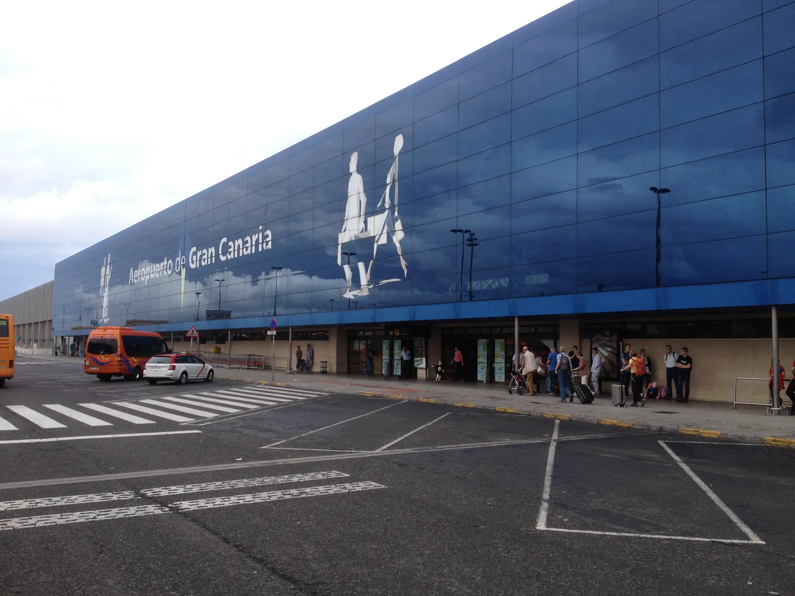 Blue glass terminal front at Gran Canaria Airport with a taxi and a minibus waiting at the kerb