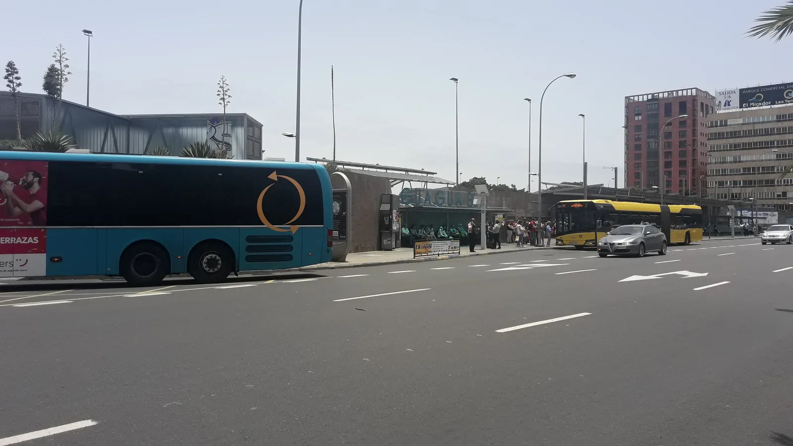 Turquoise Global intercity bus and a yellow articulated city bus at the bus station in Las Palmas