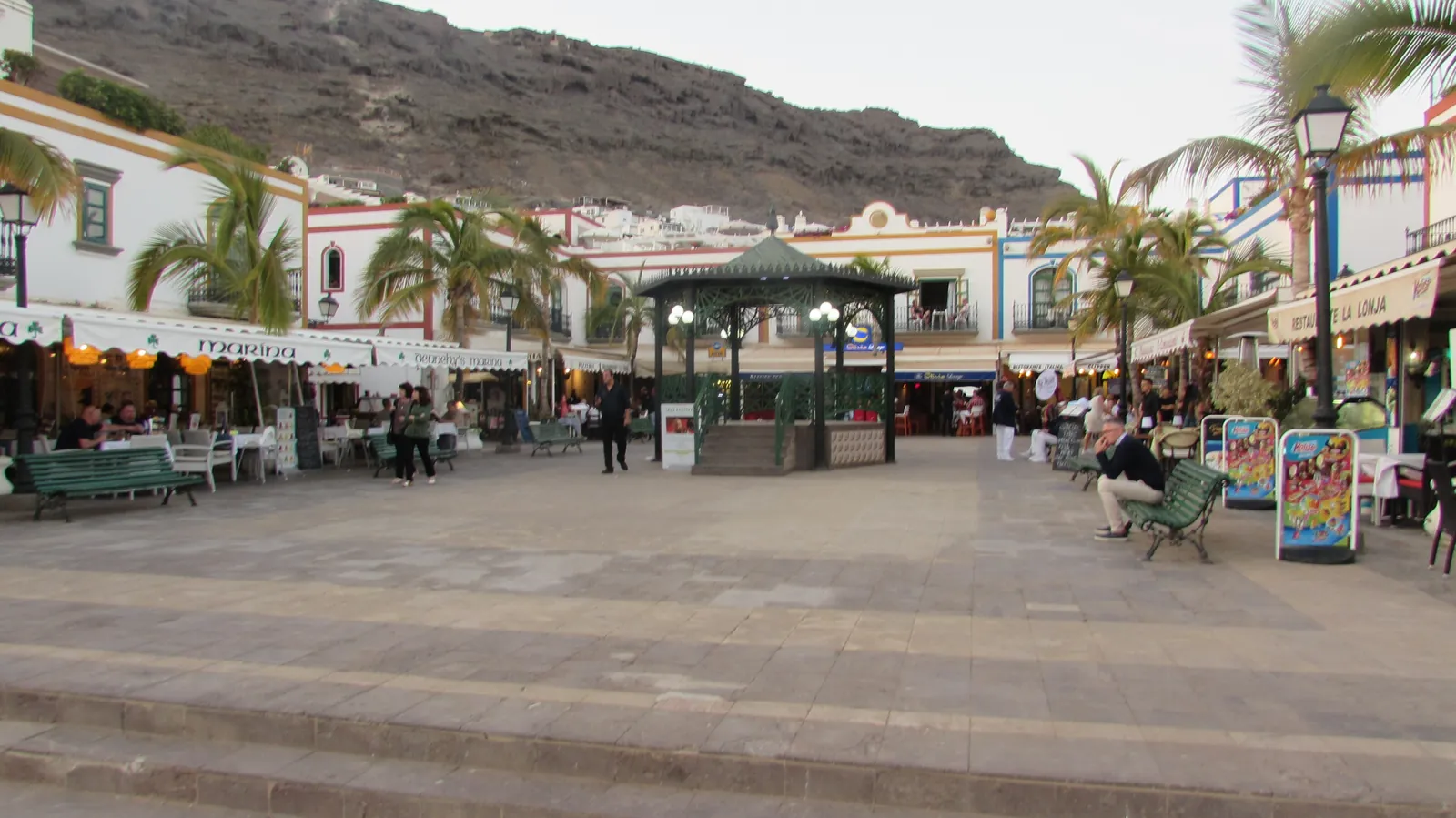 Seafront square with a bandstand and restaurant terraces in Puerto de Mogán at dusk