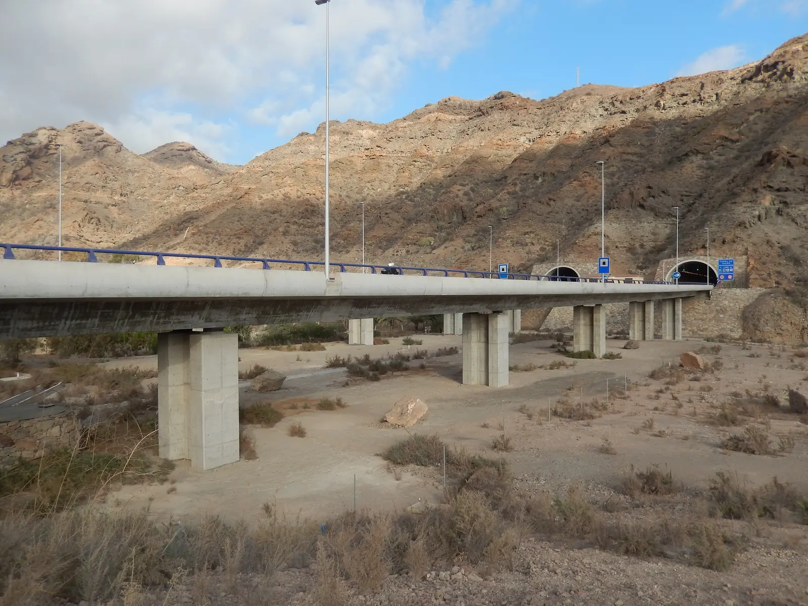 GC-1 motorway bridge crossing the Barranco de Tauro below dry brown mountains near a tunnel entrance