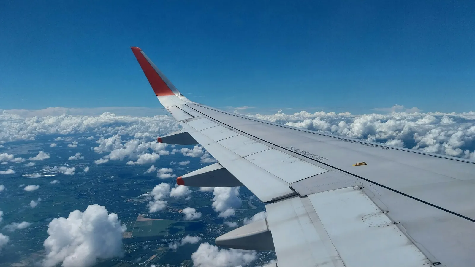 Aircraft wing above white clouds in a deep blue sky